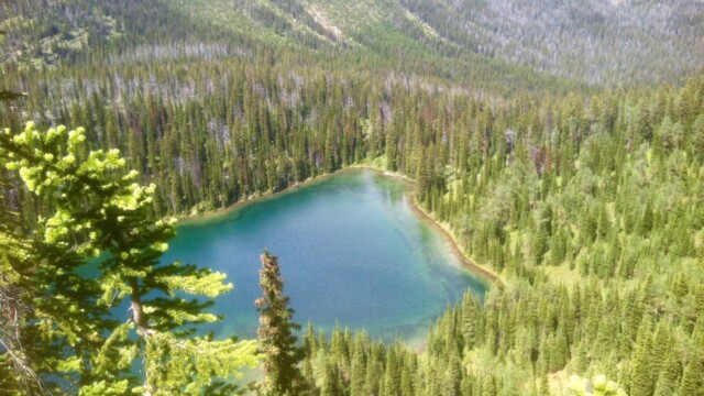 a blue lake in a valley surrounded by trees